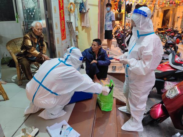图为三亚港海岸派出所辅警冯可和姐姐冯静为辖区行动不便的老人进行核酸采样