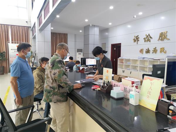 图为立案工作人员为当事人审核相关立案材料