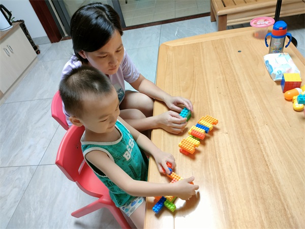 图为执勤结束，回到家中的廖小英在陪孩子玩耍