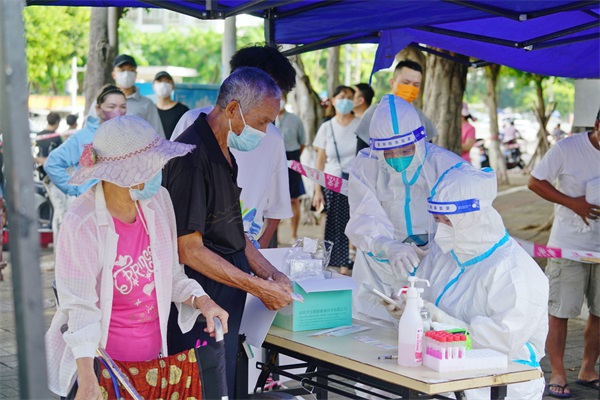 2022年8月9日，海口市龙华区人民法院志愿者在核酸采集点位协助医护人员采集市民信息。 蔡承霖 摄