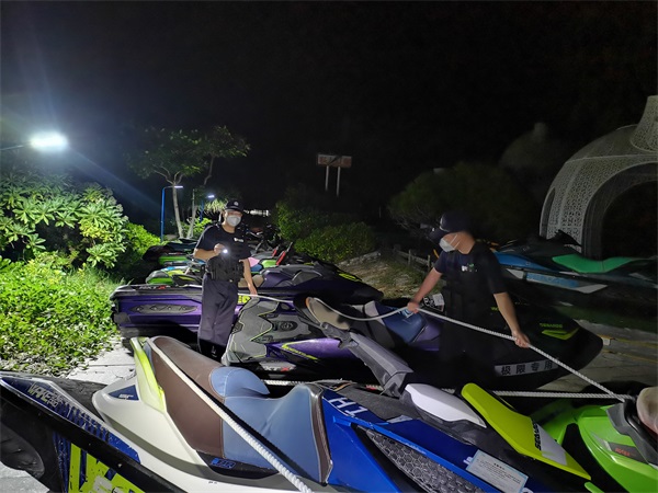 图为民警对停放的摩托艇进行巡查