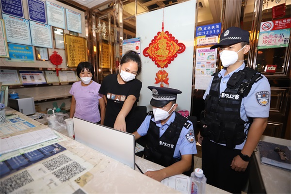 图为民警检查酒店人员入住登记情况