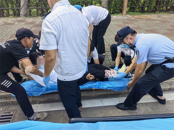图为长堤海岸派出所民警协助急救中心工作人员将受伤女子抬到担架上