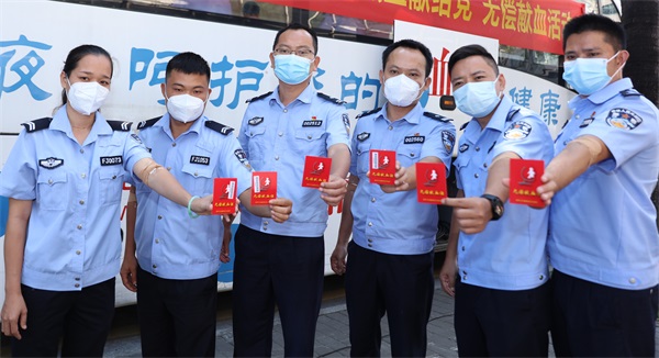图为献血的民辅警集体展示献血证