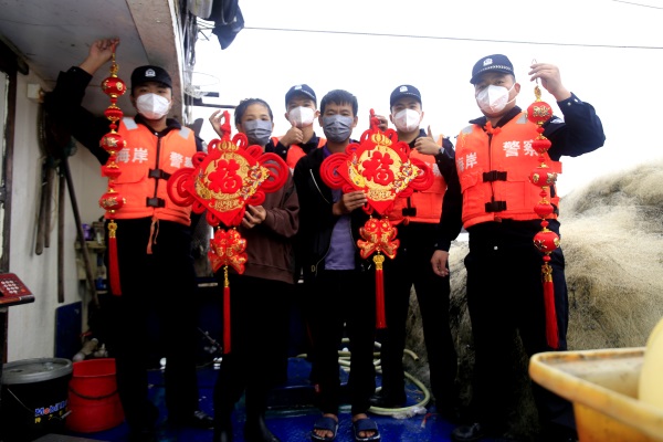 清澜海岸派出所民警向留守渔船的渔船民送上灯笼和福字等春节礼物。代龙超摄