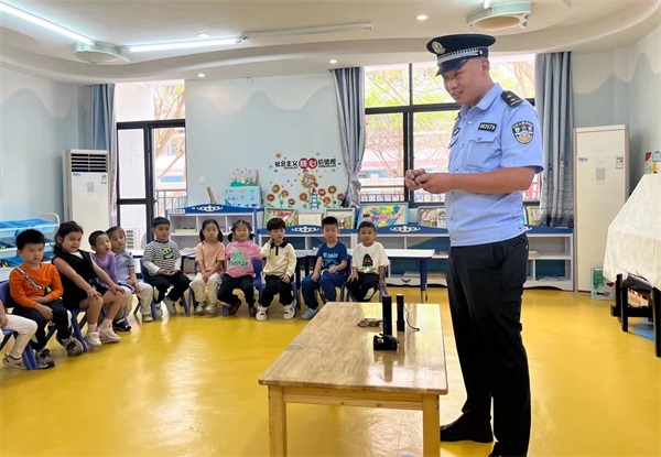 图为民警李伟为科技城第一幼儿园学生介绍基本的处警装备
