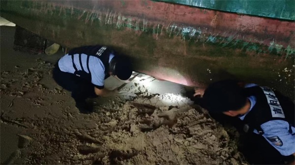 图为民警检查搁浅渔船的船底是否破损