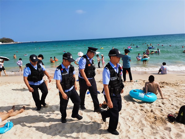 图为红沙海岸派出所民警在大东海沙滩巡逻