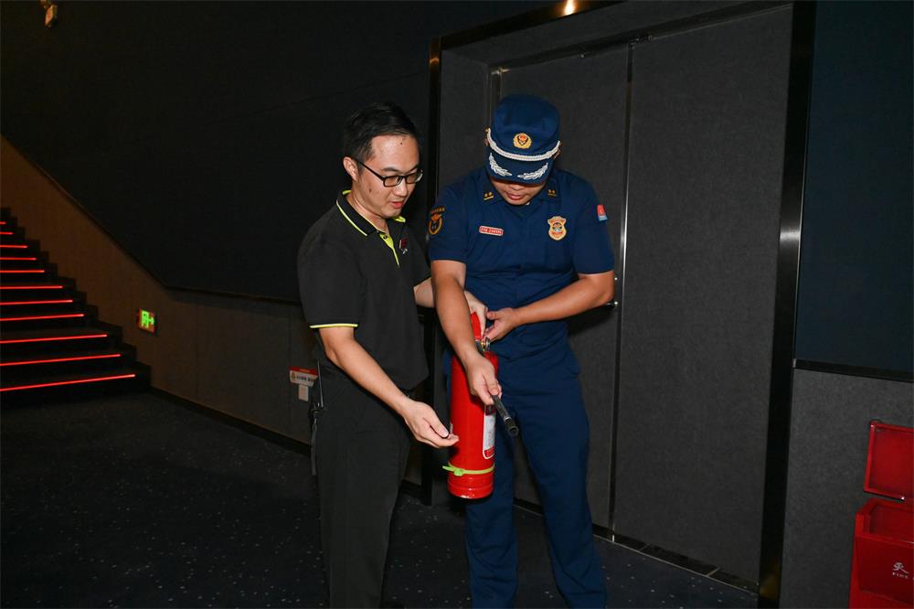 在电影院，消防人员指导工作人员如何正确使用灭火器