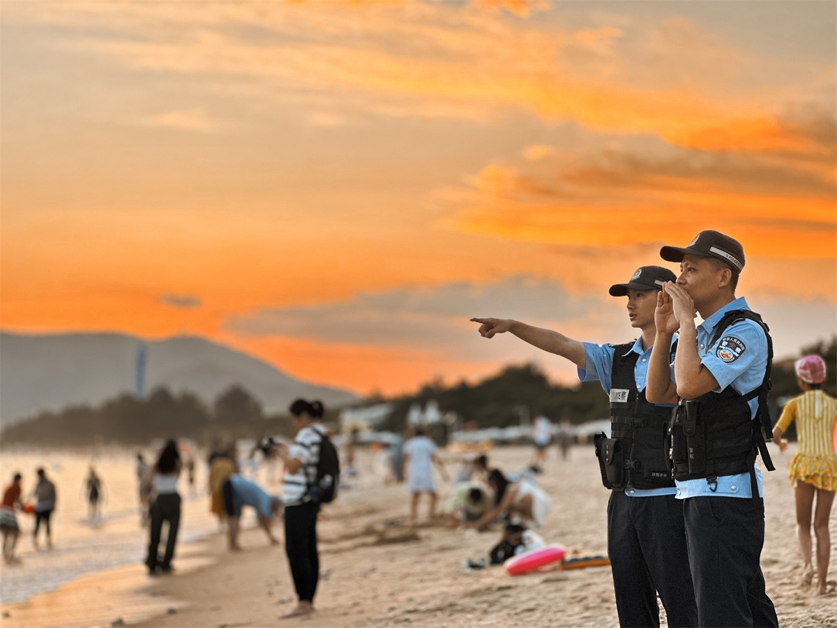 图为亚龙湾海岸派出所民警在海边提醒游客在安全海域游泳