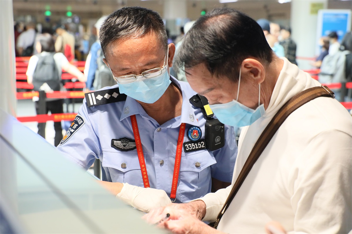 图为：美兰边检站执勤民警为入境旅客提供通关咨询帮助。摄影：李柳清