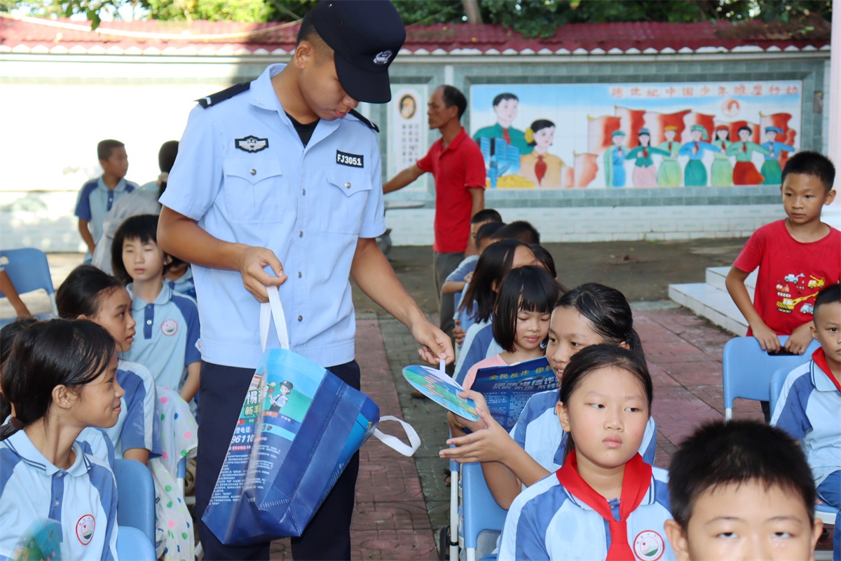 图为9月2日，万宁市公安局乌场海岸派出所民辅警向辖区保定小学学生赠送反诈扇子，开展普法宣传。代龙超摄