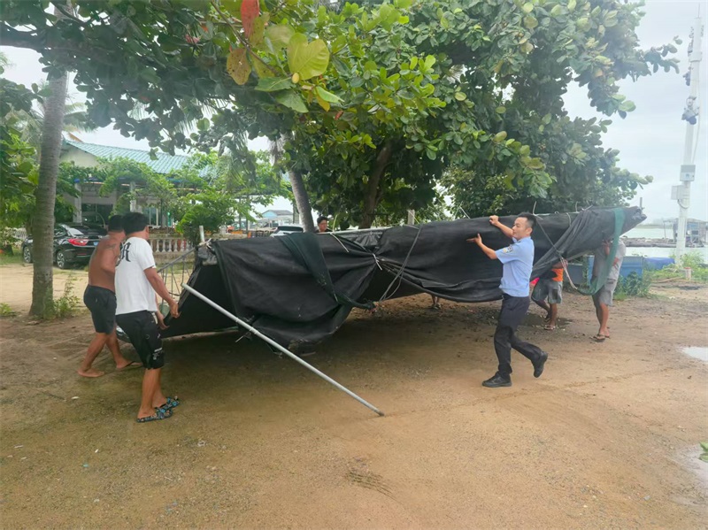 文昌市公安局口牙海岸派出所民警帮助渔船民拆撤临时雨篷,加固渔船。薛立峰摄